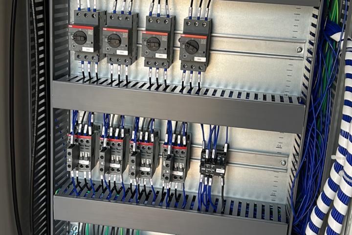Interior de painel de comando com disjuntores-motor e contatores alinhados e fiação em canaletas.