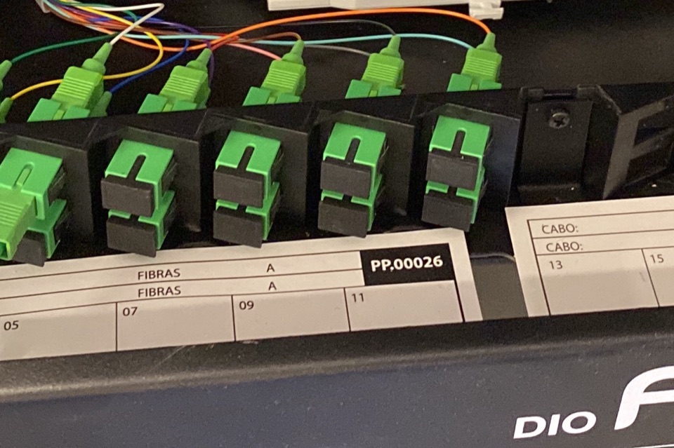 Bandeja de distribuição de fibra óptica com conectores SC/APC organizados e etiquetas de identificação.